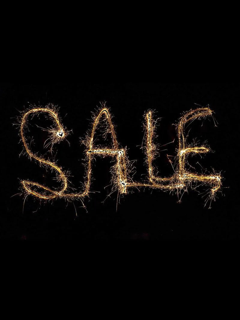 Glühende Sparkler-Schrift mit dem Wort „SALE" leuchtet in goldenen Funken vor tiefschwarzem Hintergrund und erzeugt eine festliche, dynamische Atmosphäre.