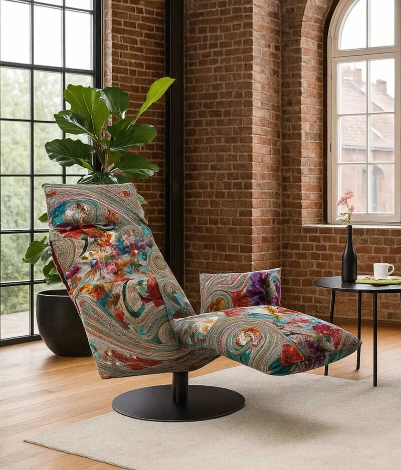 Bullfrog Relaxsessel mit floralem Mehrfarbenbezug und schwarzem Drehfuß in einem Loft mit Backsteinwand und Holzboden.