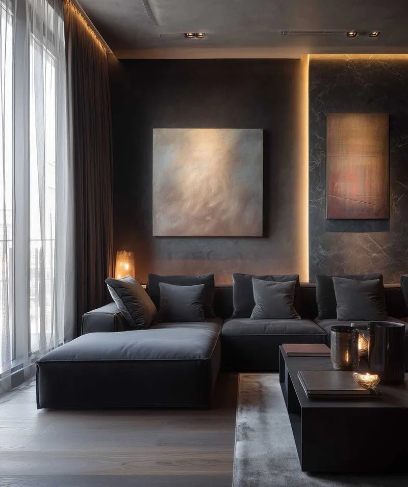 Modernes Wohnzimmer mit dunkelgraür Stoff-Eckcouch, anthrazitfarbenen Wänden, abstrakten Wandbildern und stimmungsvoller indirekter Beleuchtung in eleganter Atmosphäre.
